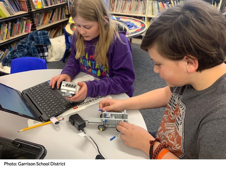 Students in a classroom with a robot and laptop
